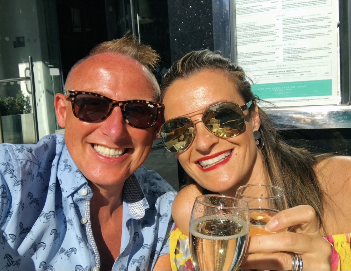 Two friends enjoying drinks together in the sunshine