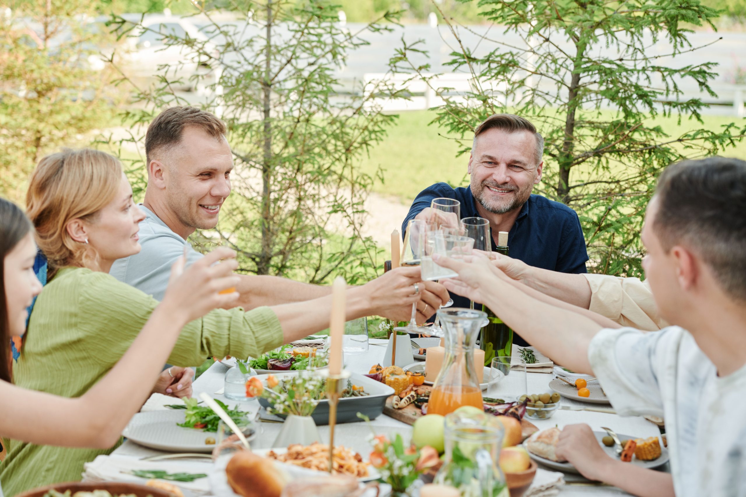 Friends raising their glasses around an outdoor meal table