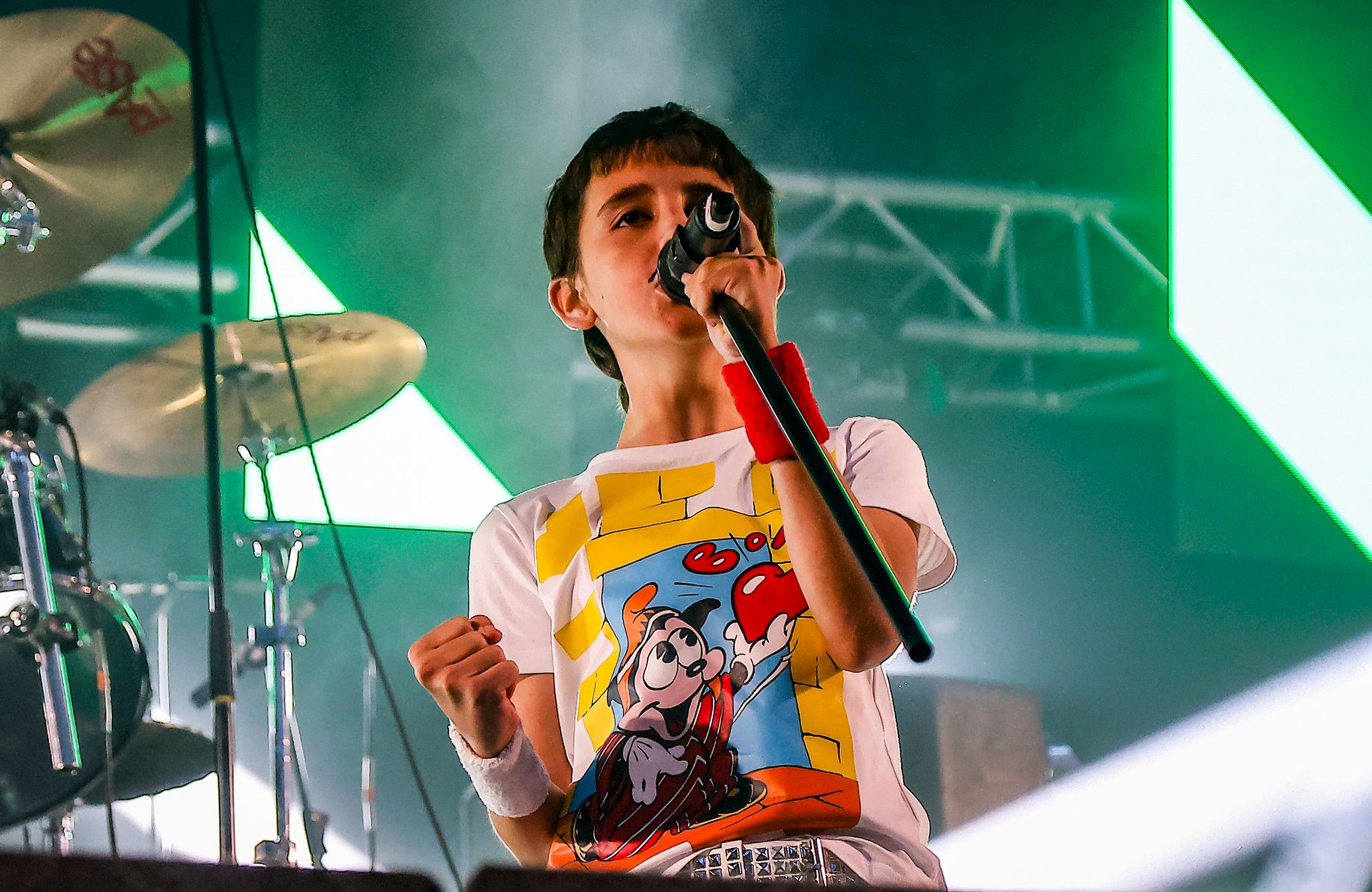 A young singer performing on stage under green lights