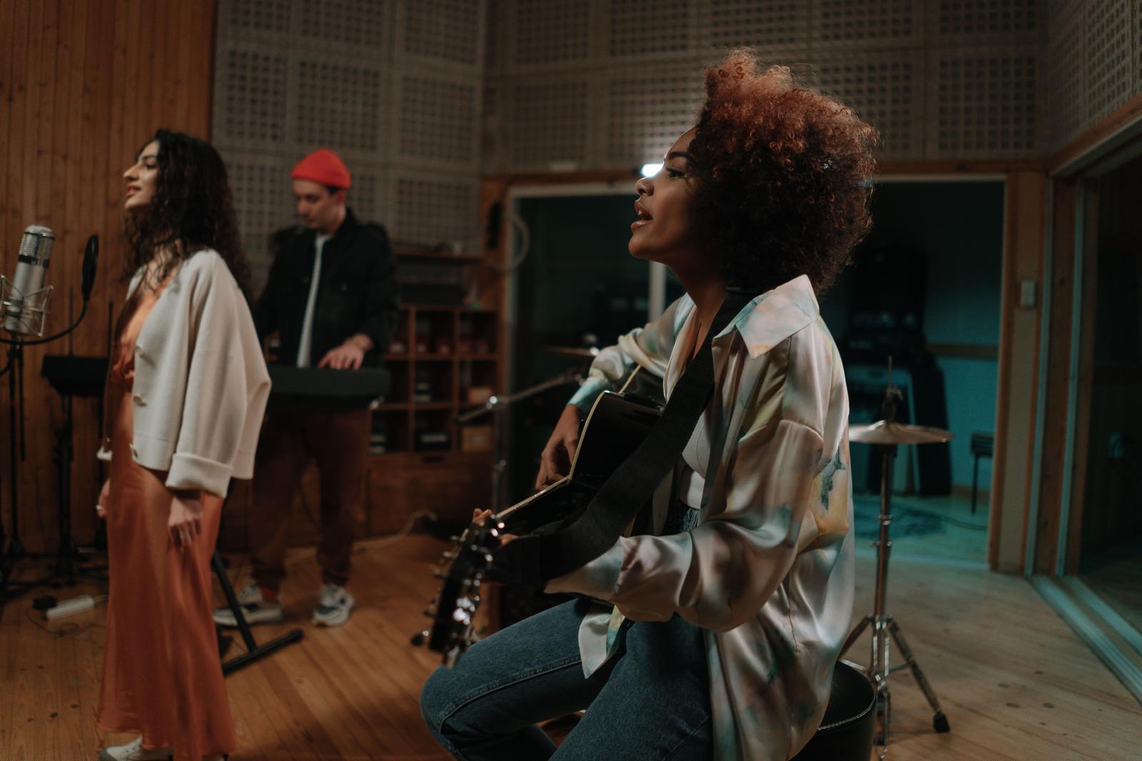 Musicians singing and playing guitar together in a recording studio