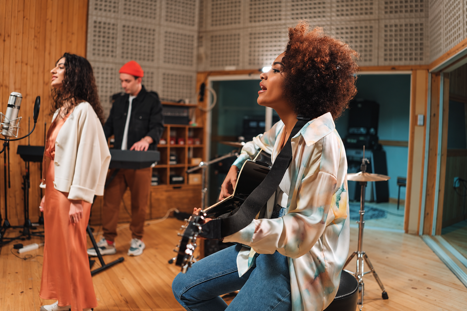 Musicians singing and playing acoustic guitar and keyboard in a recording studio